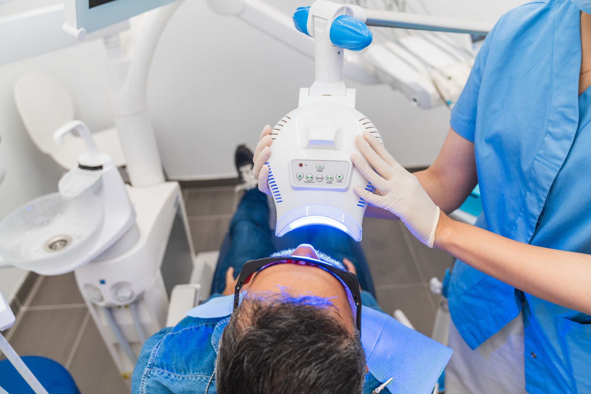 A man is getting his teeth whitened in a dentist's office
