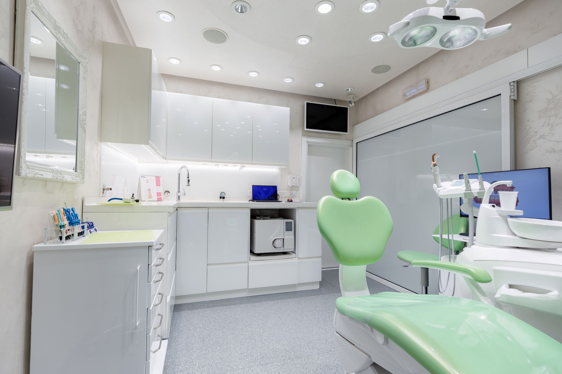 Modern dental clinic interior with green dental chair and bright lighting during daytime